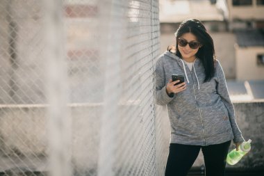 beautiful Hispanic woman using her phone after training
