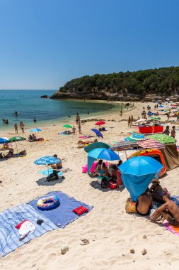 Setubal, Lizbon, Portekiz yakınlarında güneşli bir günde turist ve şemsiyelerle sahile güzel bir manzara