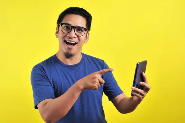 黄色の背景に隔離されたスマートフォンを使用して笑顔若い良いアジアの男の幸せ — ストック写真