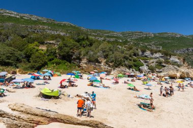 Setubal, Lizbon, Portekiz yakınlarında güneşli bir günde turist ve şemsiyelerle sahile güzel bir manzara