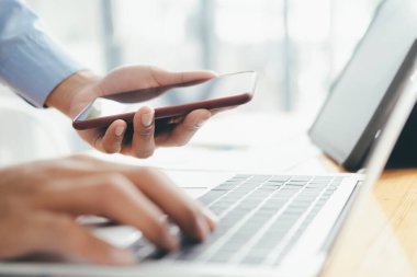 Cep telefonu kullanan ve dizüstü bilgisayarda çalışan internet gezen ya da akıllı telefondaki uygulamaları kontrol eden iş adamlarını kapat.