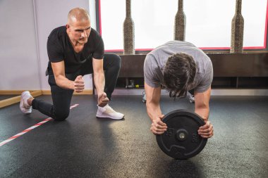 Genç adam eğitmenle kişisel eğitim yapıyor.