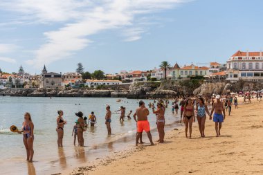 Portekiz, Lizbon yakınlarındaki Cascais 'de güneşli bir yaz haftasonu geçiren yerliler ve turistlerle dolu bir plaj.