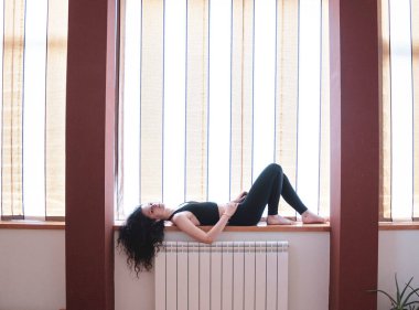 Kız pencere eşiğinde yatarken müzik dinliyor.