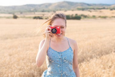 Sahada gülümseyen genç kız gün batımında fotoğraf çekiyor.