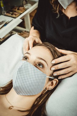 Virüs COVID için maske ve koruyucu ekranla çalışan bir güzellik uzmanı.