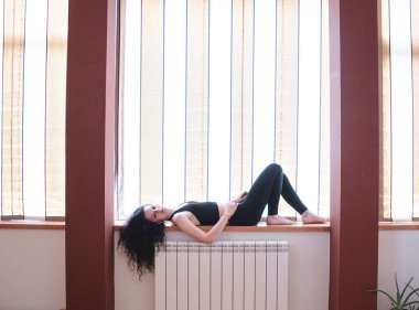 Kız pencere eşiğinde yatarken müzik dinliyor.