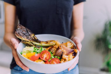 Kadın elleri sebzeli ve otlu salata tutuyor.