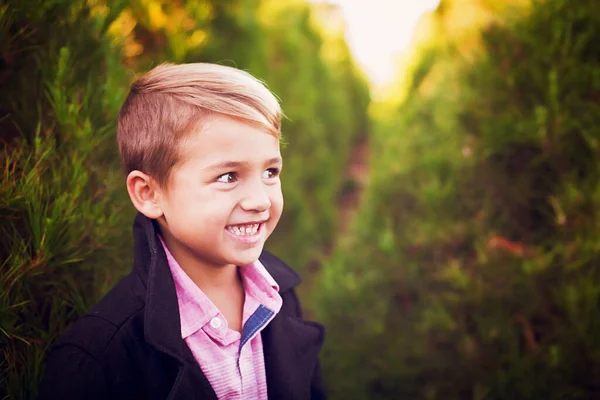 Noel Ağacı Çiftliğinde Palto Giymiş Gülümseyen Bir Çocuk — Stok fotoğraf