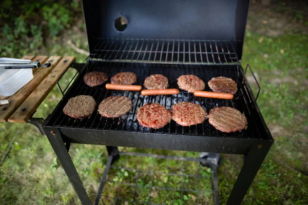在木炭户外烤架上烹调热狗和汉堡包的特写镜头 — 图库照片