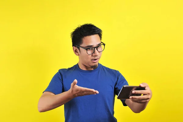 Aziatische Man Geschokt Wat Hij Ziet Smartphone Geïsoleerd Gele Achtergrond — Stockfoto