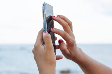 Yaz tatilinde sahilde akıllı telefonunu kullanan çekici sarışın kadın.