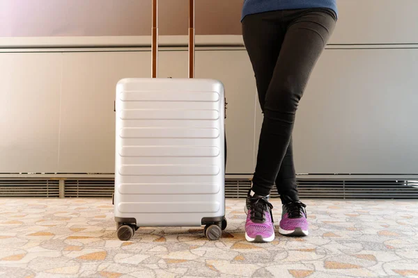 woman standing near travel luggage waiting flight in modern terminal
