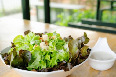 Bir kase Sezar Salatası ve ahşap masa.