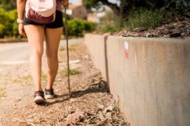 Yürüyüş yapan kişiye doğru yolu bulması ve doğru yolu izlemesi için işaret ver. Duvara boyanmış tabela. Yürüyüş turizmi kavramı. Genç bir kadın yolda yürüyor..