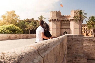 Young couple visiting the city of Valencia looking at the Serrano towers. Concept of travel and tourism on Spain.