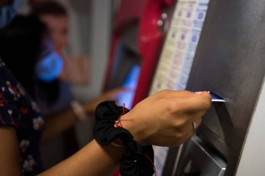 Detail photograph of a woman buying a ticket in the automatic subway machine.