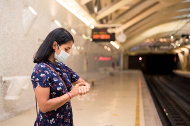 Delikanlı tren istasyonundaki akıllı saati izliyor. Arabayı bekliyor. Corona virüsü salgınında nakil kavramı.