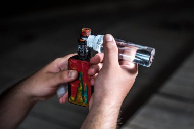 Nikotin kullanmadan sigara içmek için elektronik sigara dolduran bir adam. Makineye sıvı döken ellerin ayrıntıları