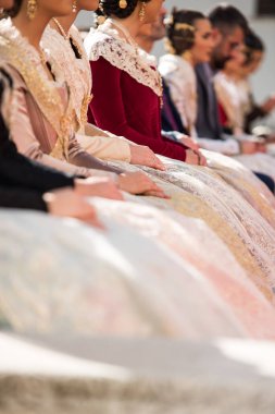 Valencia Şelaleleri 'nin tipik kostümlerindeki alerji elbiselerinin, parlak renklerin ve yansımaların yakın çekimleri. Halka açık bir eylemde oturan Falleras.