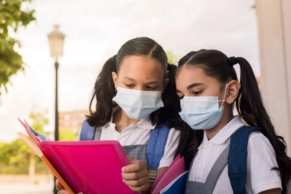 여학생들은 마스크를 야외에서 손으로 공책을 읽는다 — 스톡 사진