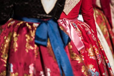 Valencia Fallas 'ın tipik elbisesinin ayrıntıları. Fotoğrafçılık, çiçek motifli eteklerden birine odaklanmış. Kırmızı elbiseler.