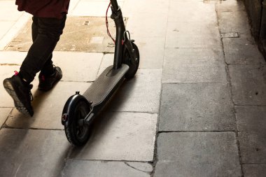 Close up photography, detail of person carrying an electric scooter through the city walking clipart