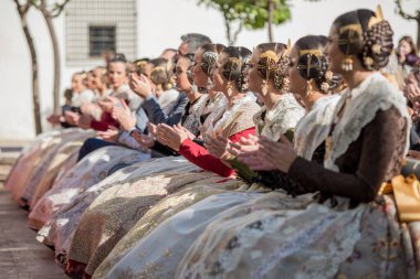 Falleras kentteki halka açık bir etkinlikte el çırpıyordu. Odaklanamayan bir grup falleras. Ellerin fotoğrafçılığını kapat.