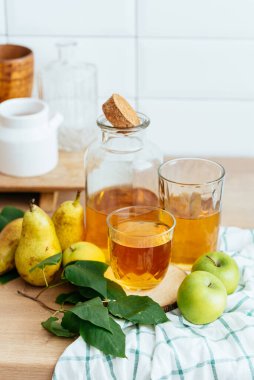 Şişede taze elma suyu, mutfakta da bardak.
