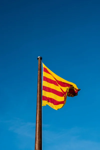 カタルーニャの旗 Senyera 赤と黄色の縞模様のフラグときれいな青空の背景に 晴れた日には風になびく旗 — ストック写真