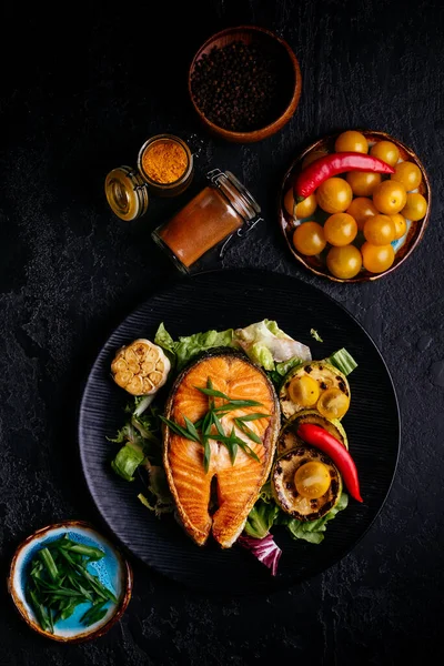 Salmon steak baked on coals with vegetables on a black background — Stock Image Salmon Steak Baked Coals Vegetables Black Background Royalty Free Stock Images