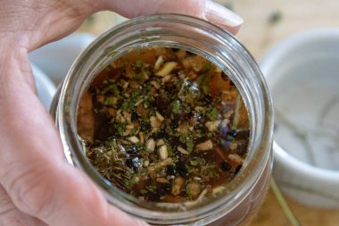 Herbal tincture steeping in glass jar with water and vodka