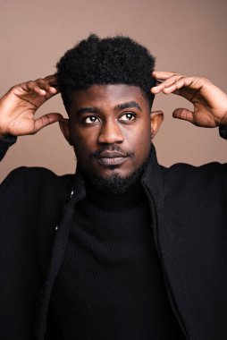 Close-up of African elegant man in black jacket posing at camera