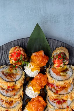 Hafif arka planda siyah bir tabakta Tempura suşi rulosu