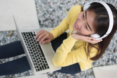 Headphon tarafından laptop dinleme müzik ile gülümseyen asyalı genç kız