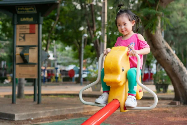 Little girl are playing seesaw in the playground. — Stock Photo, Image