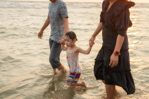 Glad asiatisk familj på stranden vid solnedgången. — Stockfoto