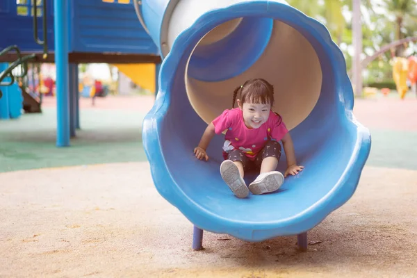 Asian baby girl playing slider at playground in the park. — Stock Photo, Image