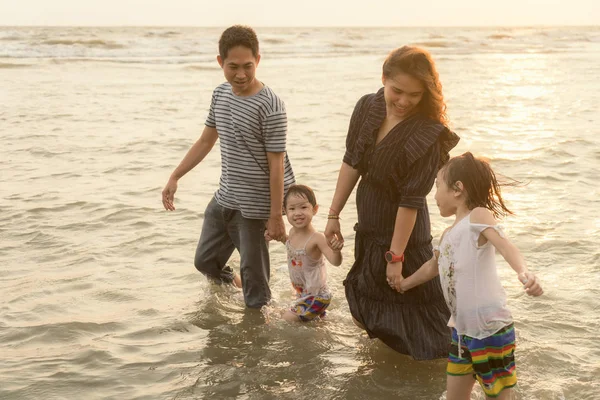 Lycklig asiatisk familj ha kul på stranden vid solnedgången. — Stockfoto