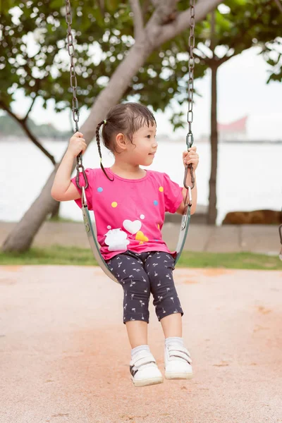 Asian little girl play on a swing at the park, little girl have — Stock Photo, Image