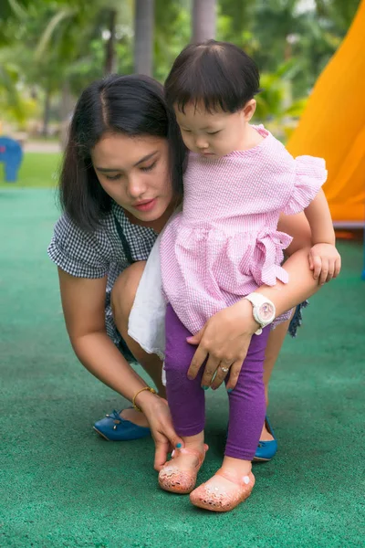 Asian young mother help daughter wearing shoes. — Stock Photo, Image