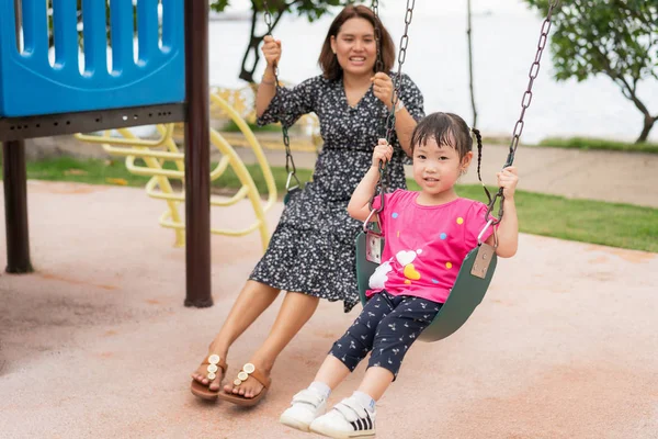 Asian young mother play on a swing with her adorable little daug — Stock Photo, Image