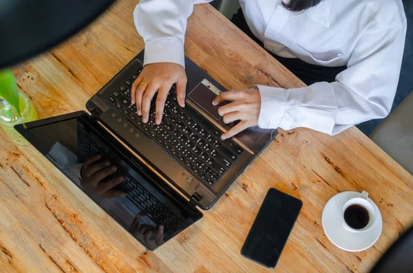 Молода жінка використовує ноутбук на дерев'яному столі — стокове фото