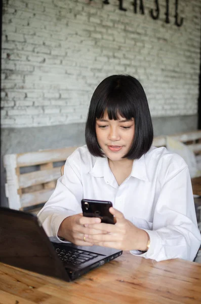 Молодая женщина, использующая смартфон в кафе — стоковое фото