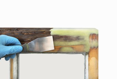 Person applying resin with spatula to old sash window  clipart