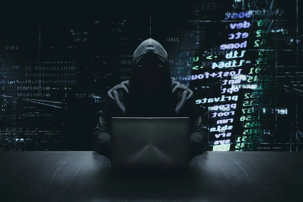 バイナリ コードの背景の前で自分のコンピューターで匿名のハッカー ストック画像