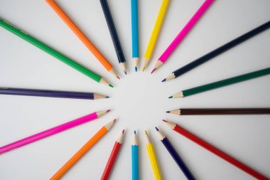 Beyaz arkaplanda renk tekerleği renklerine göre düzenlenmiş renkli kalemler