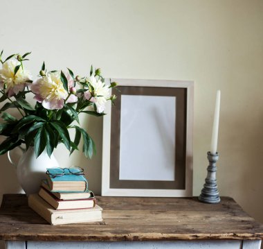 Antika iç mekan, masanın üstünde duran duvar şakayık buketi, kitap ve şamdanla fotoğraf ve resim için çerçeve.