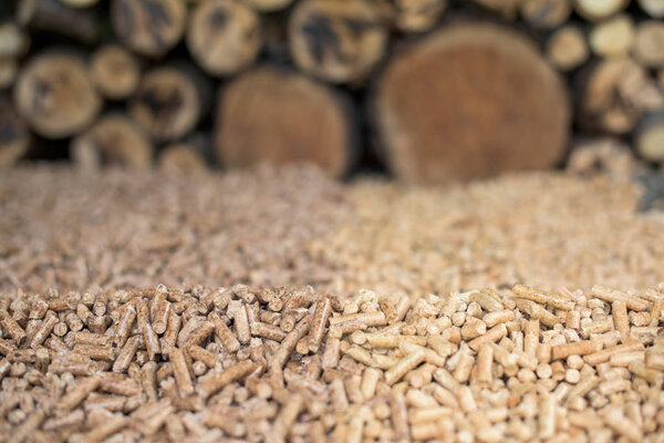 Pile of Oak and pine pellets in front of pile of wood