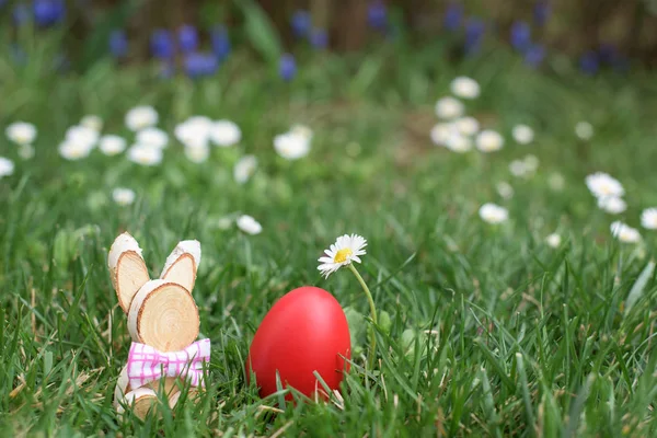 Easter hunt - red egg and wooden bunny — Stock Photo, Image